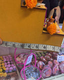Yellow fabric with decorative elements and a ruler for scale, with a blurred background of products.